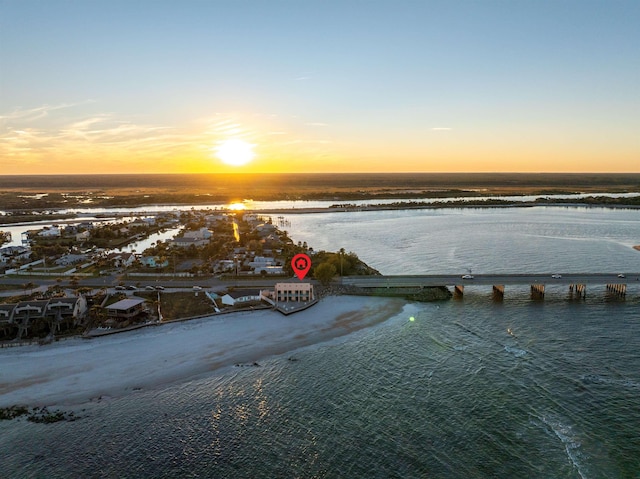 aerial view at dusk with a water view and a view of the beach