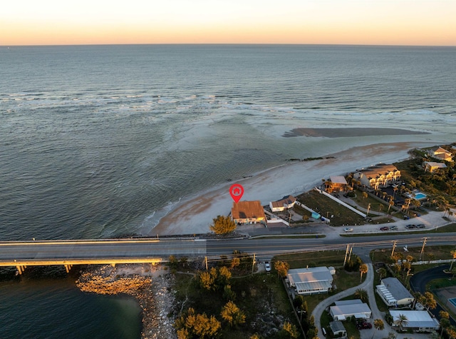 aerial view at dusk with a view of the beach and a water view