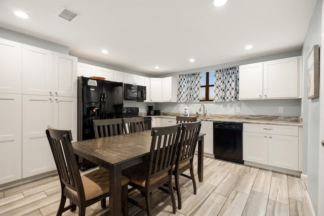 kitchen featuring sink, white cabinets, black appliances, and light hardwood / wood-style floors