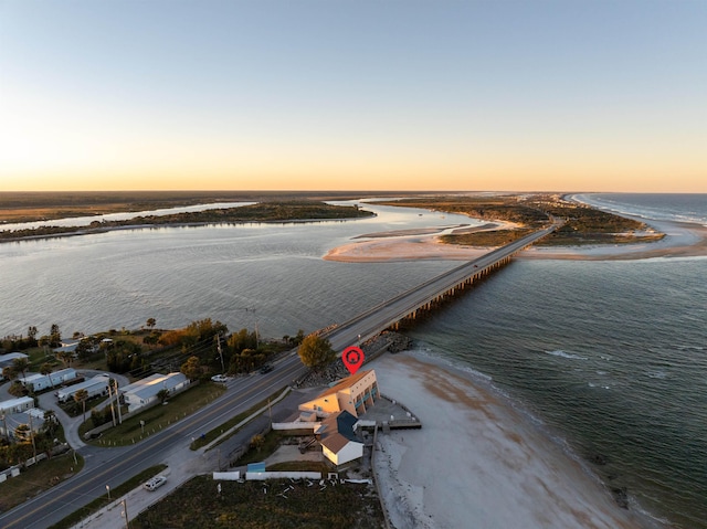 aerial view at dusk with a water view and a view of the beach