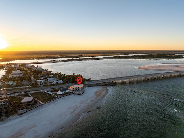 aerial view at dusk with a view of the beach and a water view