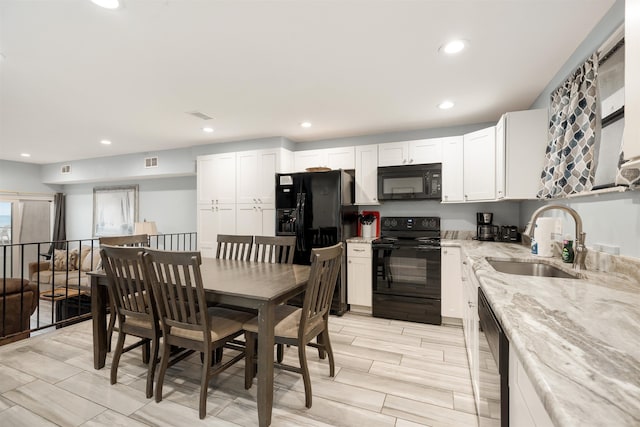 kitchen with light stone countertops, sink, black appliances, light hardwood / wood-style flooring, and white cabinets