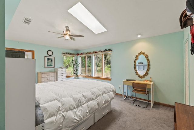 bedroom featuring carpet floors, a skylight, a ceiling fan, visible vents, and baseboards