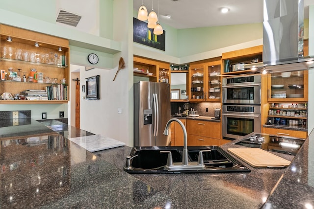 kitchen featuring stainless steel appliances, a sink, visible vents, brown cabinetry, and island exhaust hood