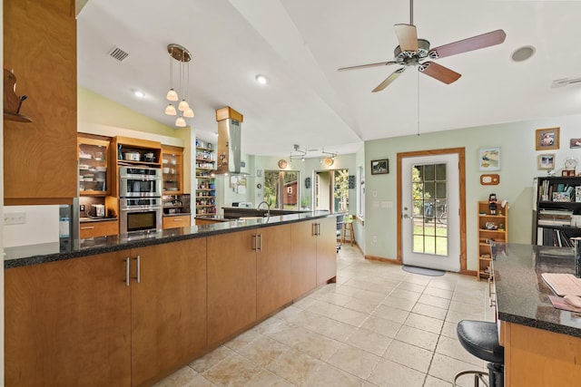 kitchen featuring double oven, light tile patterned flooring, visible vents, vaulted ceiling, and island exhaust hood