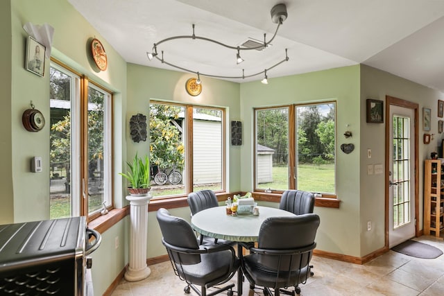 dining space featuring light tile patterned floors, baseboards, and rail lighting