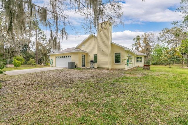 view of side of property featuring an attached garage, cooling unit, concrete driveway, a yard, and a chimney