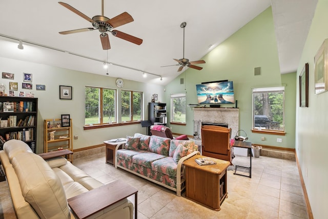 living area featuring baseboards, visible vents, rail lighting, a fireplace, and high vaulted ceiling