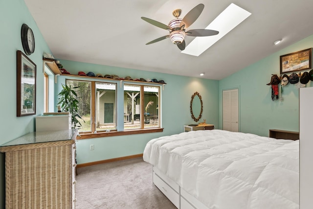 carpeted bedroom with lofted ceiling with skylight, baseboards, and a ceiling fan