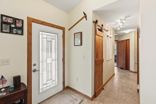 entrance foyer featuring rail lighting, a barn door, light tile patterned floors, and baseboards