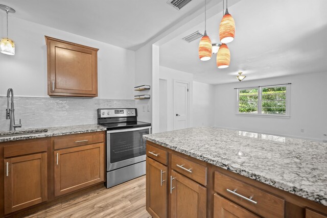 1617 Cleveland Ave, Palatka, FL 32177 - kitchen featuring stainless steel electric range, a sink, light wood-style floors, brown cabinets, and light stone countertops
