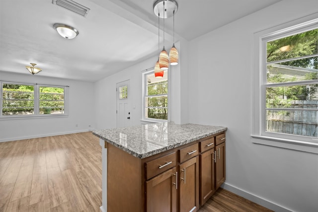 1617 Cleveland Ave, Palatka, FL 32177 - kitchen featuring light stone countertops, light wood-style flooring, hanging light fixtures, baseboards, and brown cabinetry