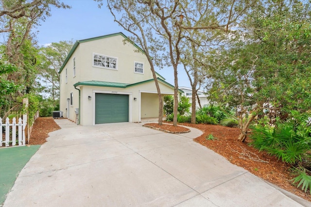 view of front of house with a standing seam roof, metal roof, fence, a garage, and driveway