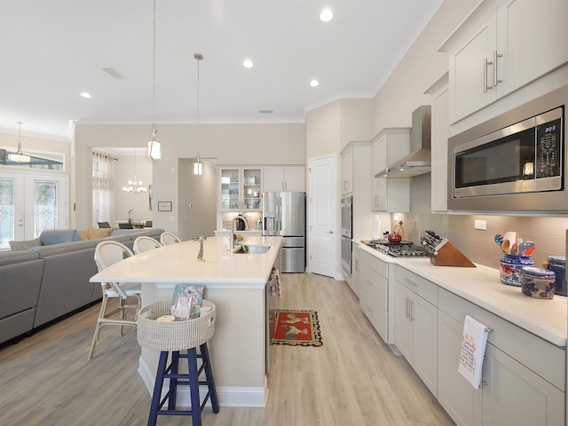 100 Coppinger Pl, Saint Johns, FL 32259 - kitchen featuring wall chimney range hood, appliances with stainless steel finishes, a kitchen bar, crown molding, and open floor plan