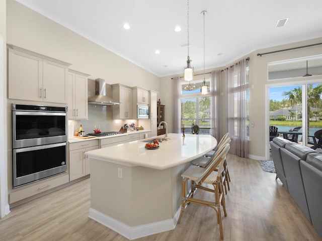 100 Coppinger Pl, Saint Johns, FL 32259 - kitchen with wall chimney range hood, appliances with stainless steel finishes, light wood-style flooring, an island with sink, and recessed lighting