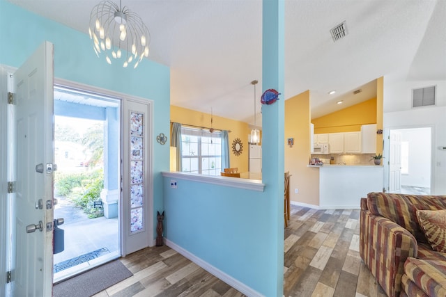 foyer with an inviting chandelier, lofted ceiling, and wood-type flooring