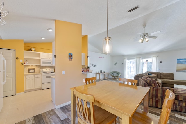 dining space with light hardwood / wood-style floors, lofted ceiling, ceiling fan, and a textured ceiling