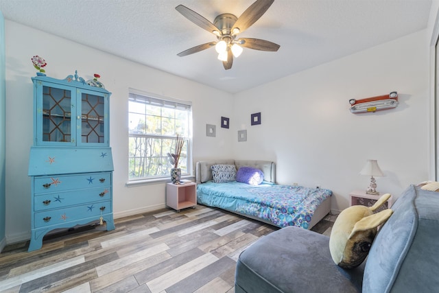 bedroom with ceiling fan, a textured ceiling, and hardwood / wood-style floors