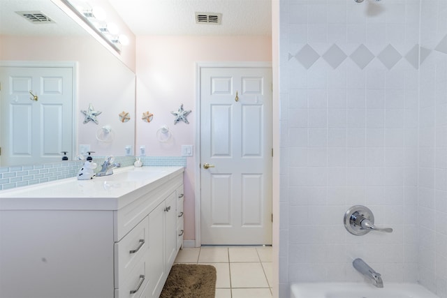 bathroom with vanity, tiled shower / bath, a textured ceiling, and tile patterned floors