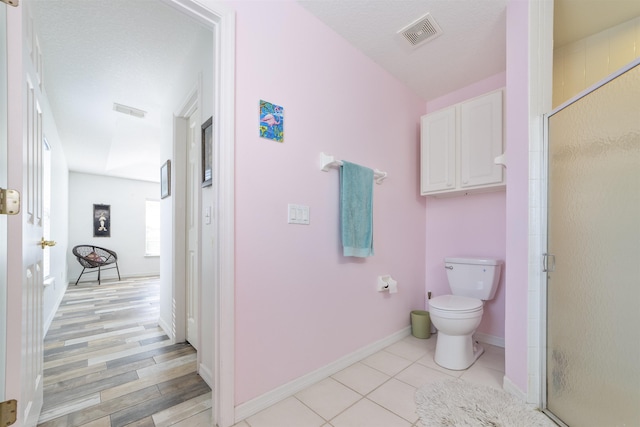 bathroom featuring tile patterned flooring, toilet, and walk in shower