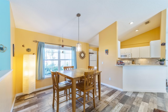 dining space with hardwood / wood-style floors and vaulted ceiling