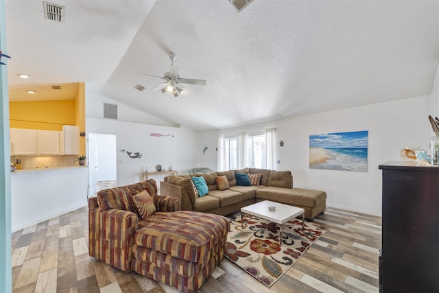 living room featuring a textured ceiling, ceiling fan, vaulted ceiling, and light hardwood / wood-style floors