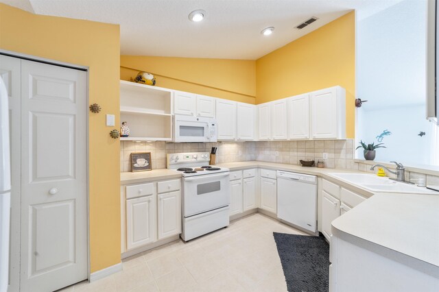 kitchen featuring tasteful backsplash, white appliances, lofted ceiling, sink, and white cabinetry