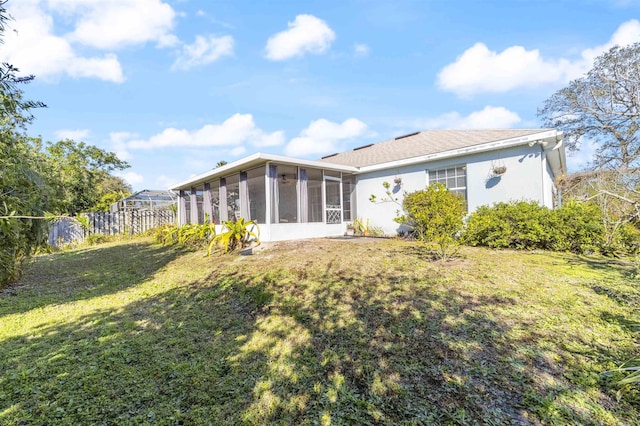 back of house with a sunroom and a lawn