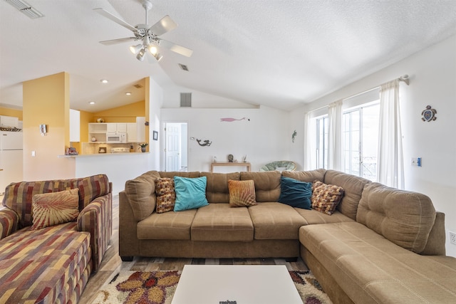 living room featuring vaulted ceiling, ceiling fan, and a textured ceiling