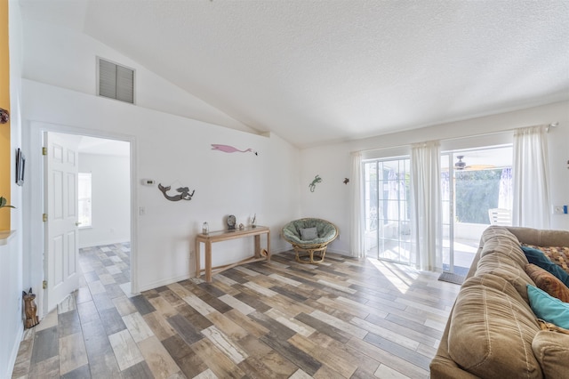 living area with light wood-type flooring, a textured ceiling, and lofted ceiling