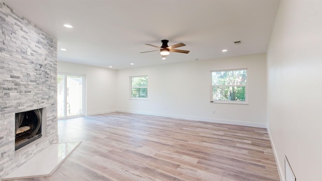 unfurnished living room with ceiling fan, a fireplace, and light hardwood / wood-style flooring