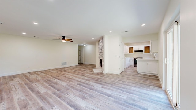 unfurnished living room featuring a fireplace, light wood-type flooring, and ceiling fan