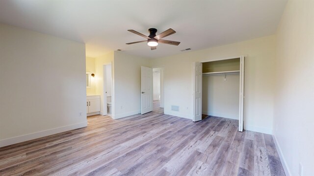 unfurnished bedroom with light wood-type flooring, ensuite bathroom, a closet, and ceiling fan