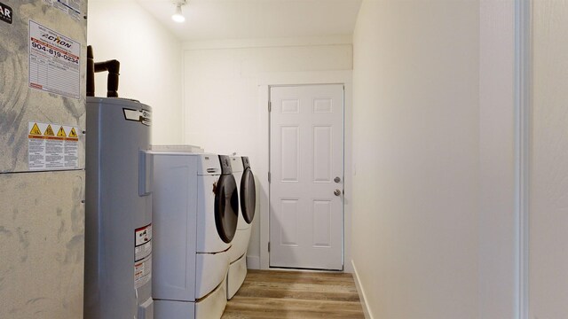 clothes washing area featuring light wood-type flooring, washing machine and dryer, and electric water heater