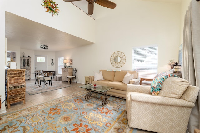 living room with tile patterned floors, ceiling fan, and a high ceiling