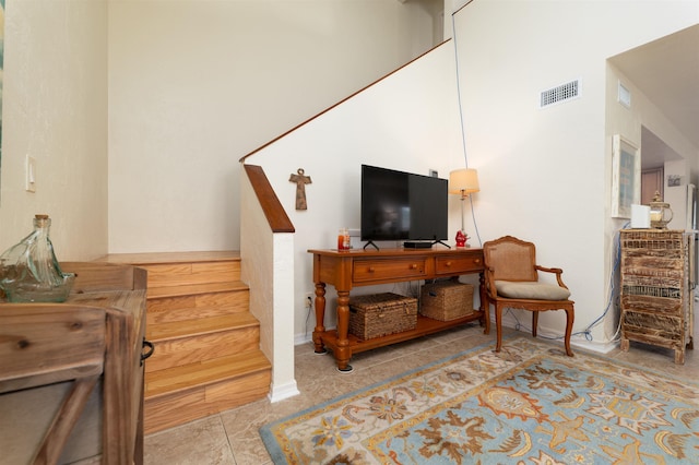 living area with light tile patterned floors and a high ceiling