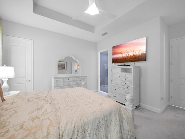 bedroom with light colored carpet, a raised ceiling, and ceiling fan