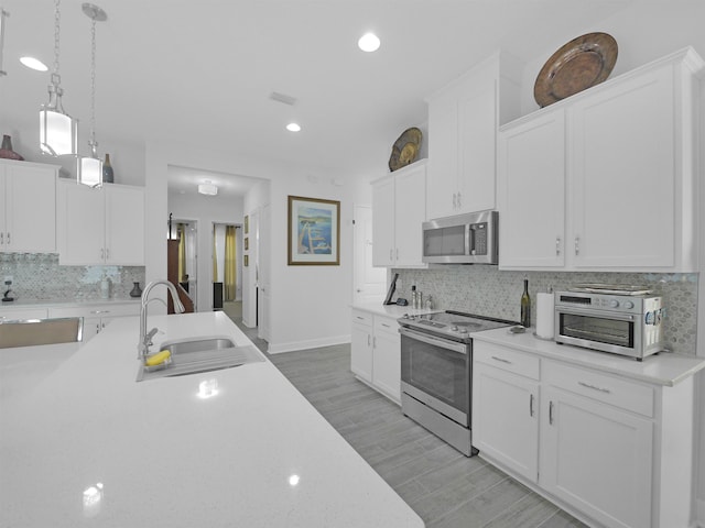 kitchen featuring decorative light fixtures, white cabinetry, sink, and appliances with stainless steel finishes