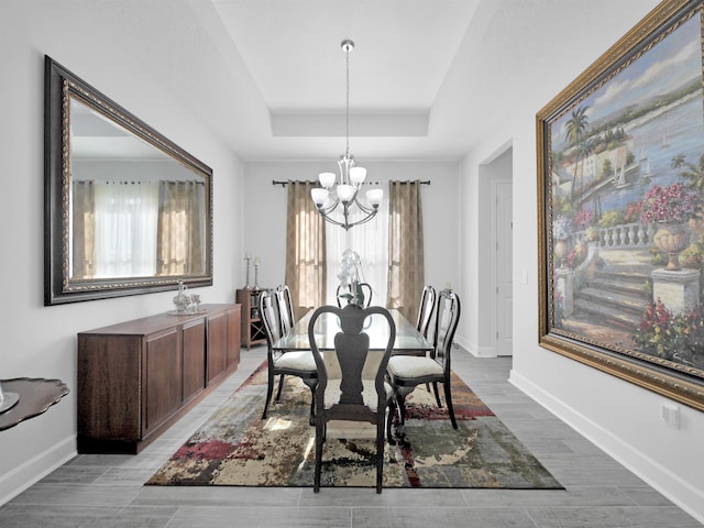 dining space featuring a raised ceiling and an inviting chandelier