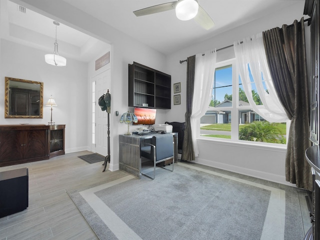 office space with ceiling fan, light hardwood / wood-style floors, and a raised ceiling