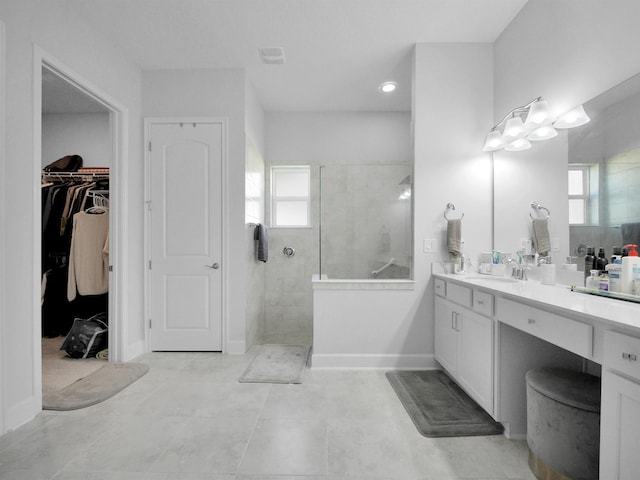 bathroom featuring tile patterned floors, a wealth of natural light, vanity, and tiled shower