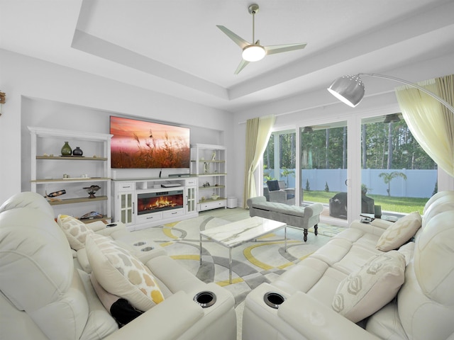 living room with a raised ceiling and ceiling fan