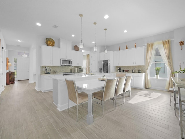 kitchen featuring white cabinets, a large island, pendant lighting, and appliances with stainless steel finishes