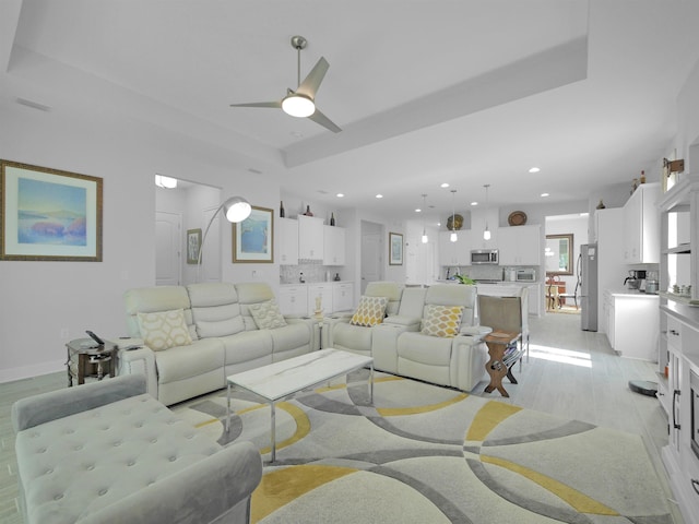 living room with a raised ceiling and ceiling fan