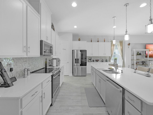 kitchen featuring white cabinets, hanging light fixtures, sink, appliances with stainless steel finishes, and tasteful backsplash