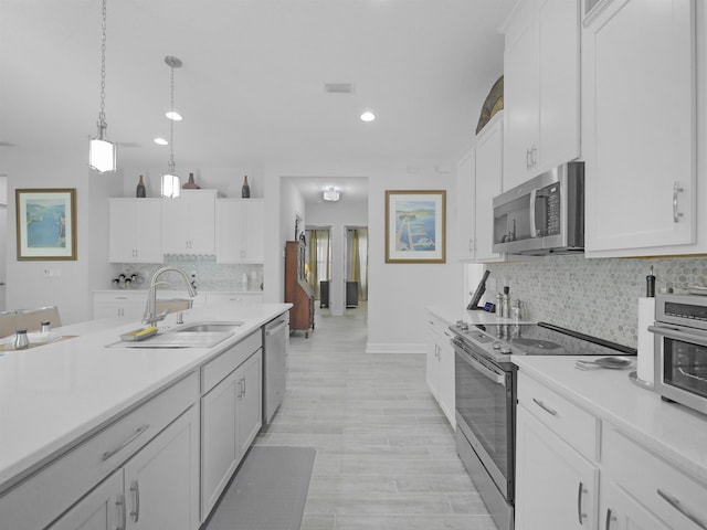 kitchen featuring sink, hanging light fixtures, appliances with stainless steel finishes, tasteful backsplash, and white cabinetry