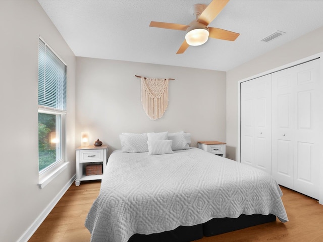 bedroom featuring a textured ceiling, a closet, ceiling fan, and light wood-type flooring