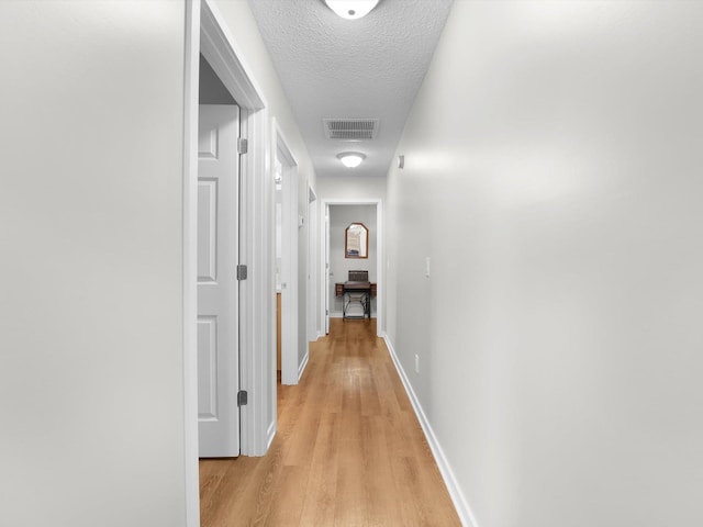 hallway featuring a textured ceiling and light wood-type flooring