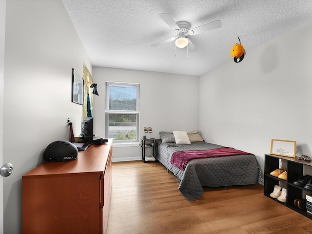 bedroom with ceiling fan, light hardwood / wood-style flooring, and a textured ceiling