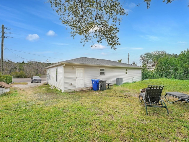 rear view of property featuring a yard and central AC unit